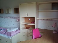 Finální realizace interiéru dětského pokoje, záběr na postel, židle, stůl a skříň